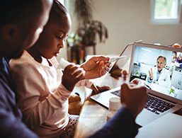 Man and child talking to doctor via a laptop